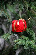 Suspension cadeau en feutre rouge à ruban doré sur une branche de sapin
