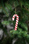 Suspension sucre d'orge en feutre rouge et blanc sur une branche de sapin