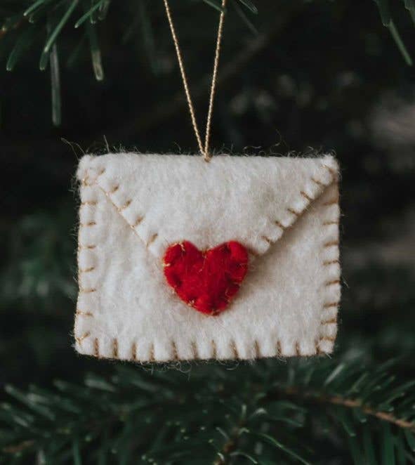 Pale felt envelope ornament with a red heart on a fir branch
