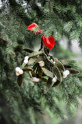 Green felt mistletoe with white berries and a red bow on a Christmas tree