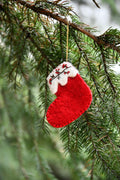 Chaussette en feutre rouge à revers clair brodé sur une branche de sapin